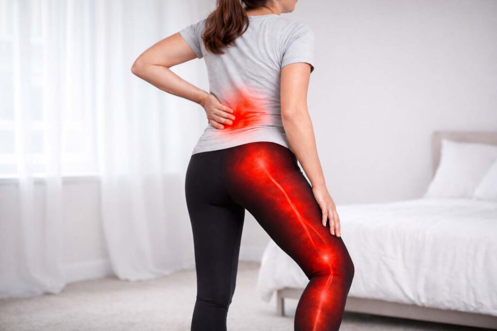 Woman holding lower back and leg showing sciatica pain symptoms