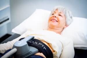 Smiling patient receiving EMSCULPT Neo abdominal muscle toning treatment in Santa Barbara clinic