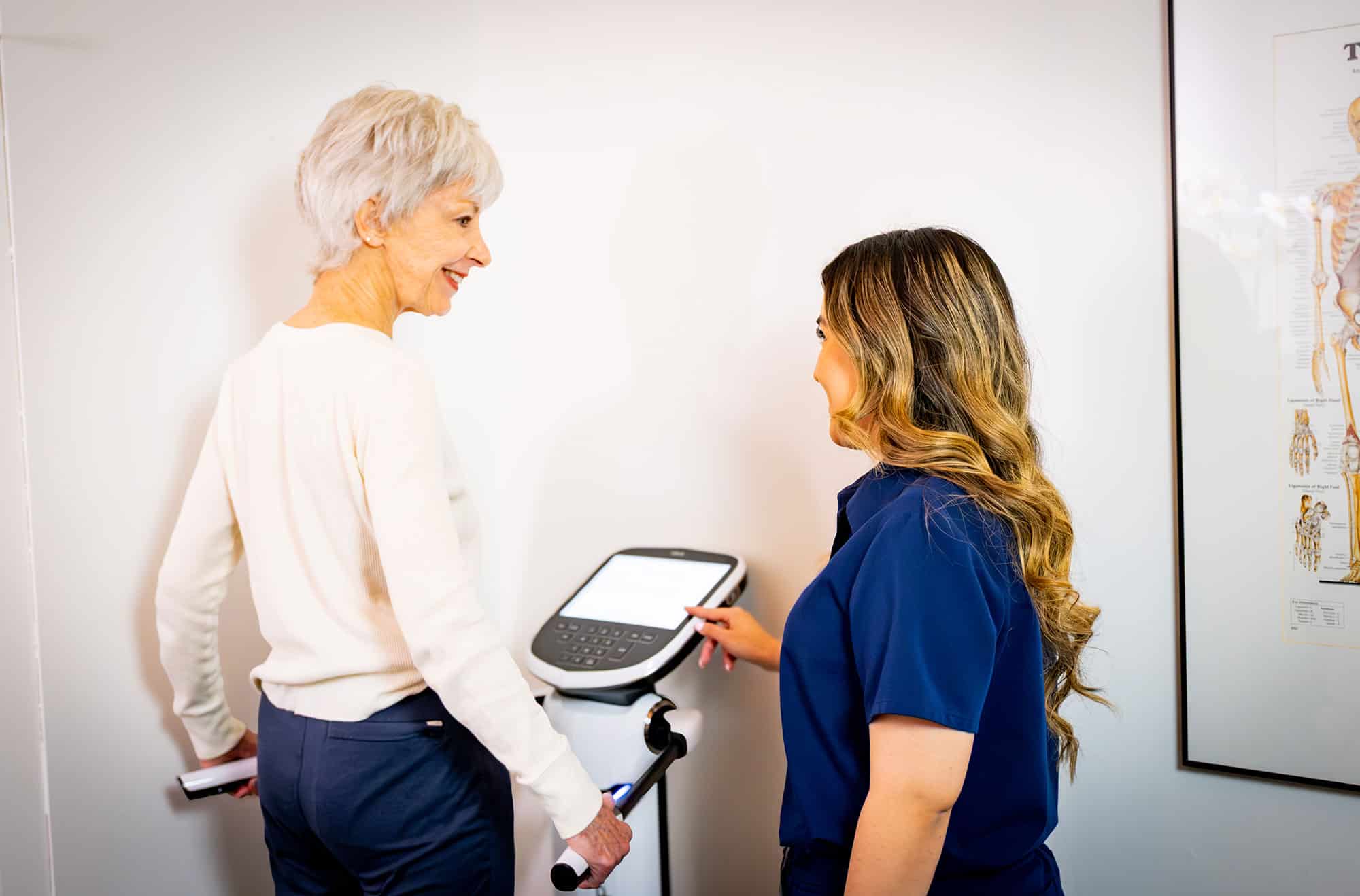 Senior patient completing a body composition assessment with a clinician using a medical body analysis device during a wellness evaluation.
