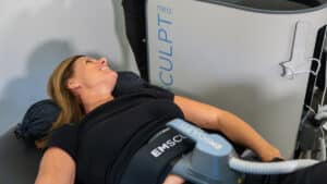 Woman receiving an Emsculpt Neo body contouring and muscle-building treatment with a provider monitoring the device.