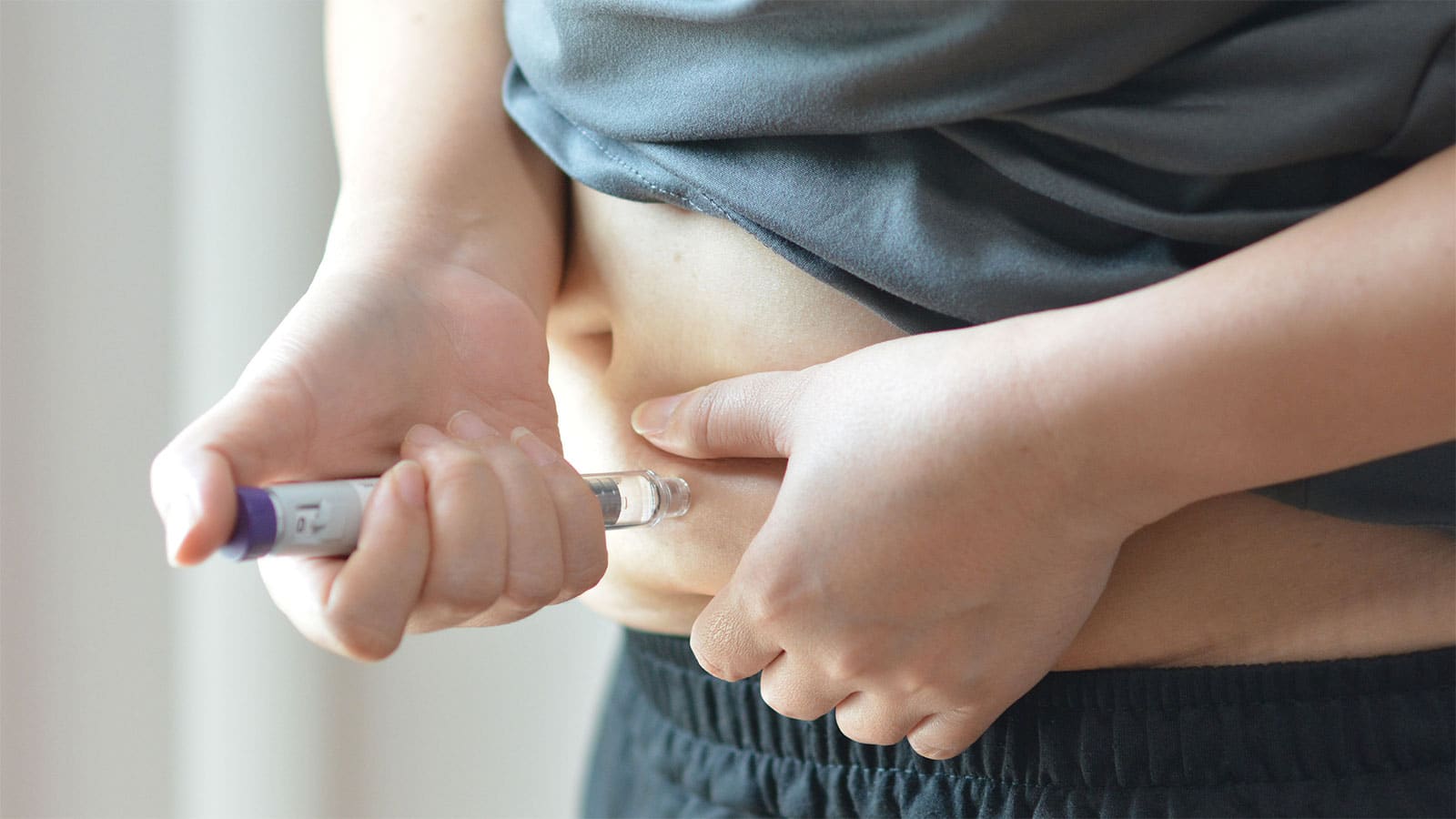Person administering a self-injection into the abdomen as part of a medical weight loss treatment.