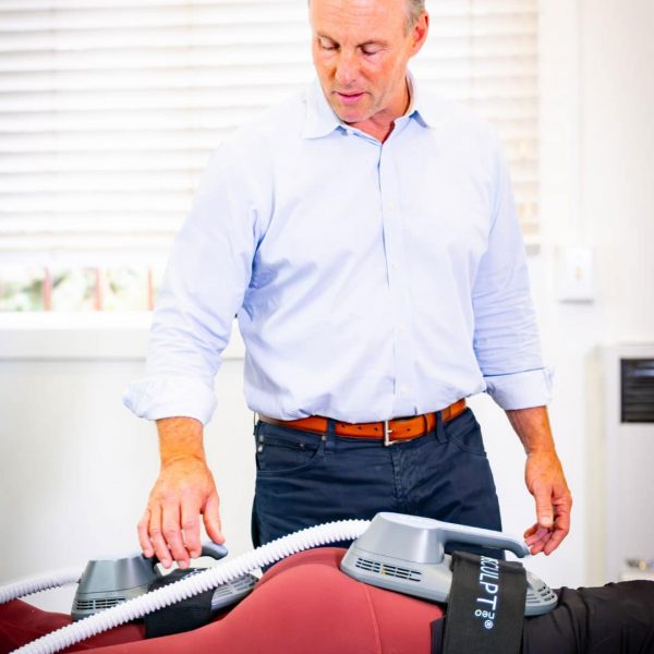 Therapist using advanced body sculpting device on patient during treatment session
