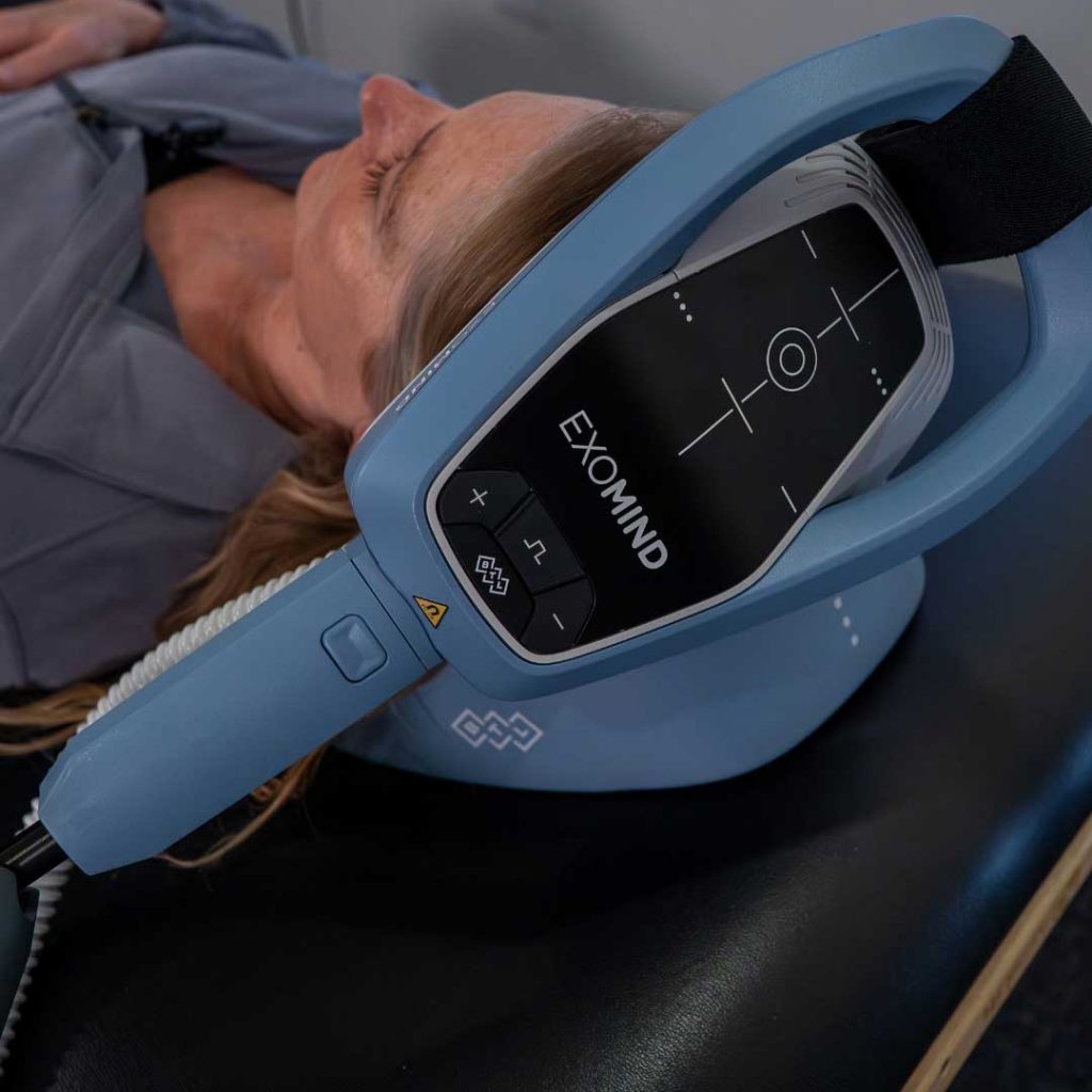 Close-up of an Exomind neurostimulation device positioned on a patient's head during a mental wellness treatment session.